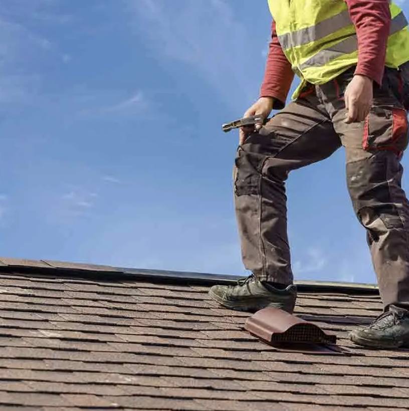 Roofer fitting a vent on a shingle roof
